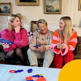 Tres personas de distintas generaciones divirtiéndose y jugando al juego de mesa Crack List